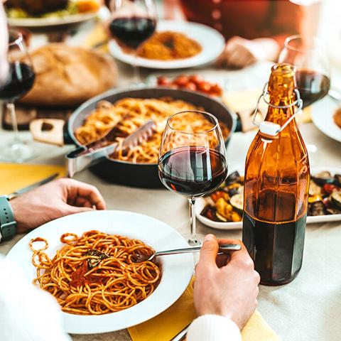 Pasta and Italian food on table with people eating in restaurant